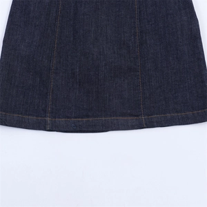 Détail de l'ourlet en denim bleu foncé avec surpiqûres orange sur une robe décontractée