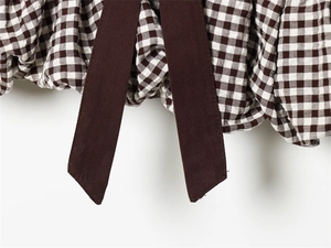 Makro-Detail von braunem Gingham-Stoff mit Faltenstruktur und dunkelbraunen Bändern