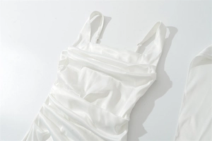 Detail of white satin dress featuring ruched chest design and smooth glossy fabric