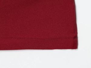 Detail shot of high-quality dark red fabric showing precise stitching and hem finish