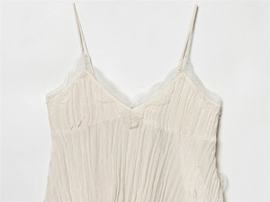 Detailansicht eines cremeweißen Camisole-Tops mit Raffungen und feiner floraler Spitze