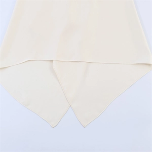 Beige halter neck top featuring asymmetric crossover hemline and draped chiffon texture