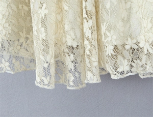 Detail of delicate floral lace fabric with intricate embroidery on elegant cream dress