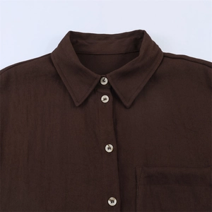 Detail of dark brown shirt with classic collar, buttons, and square chest pocket