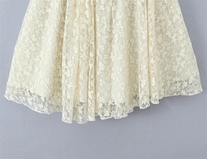 Close-up of floral lace hem with delicate wavy scalloped edges on a cream dress