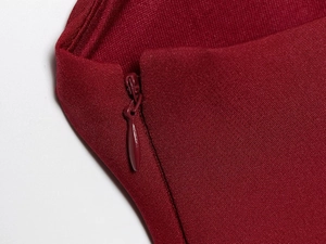 Detail of a red dress featuring a seamless concealed zipper and smooth woven fabric texture