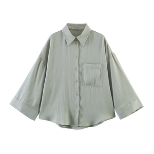 Detail view of the pale grey-green shirt featuring a classic collar and front pocket