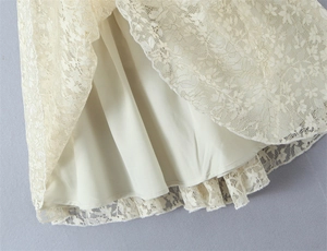 Detailed macro view of off-white floral lace fabric with a smooth lining and scalloped edge