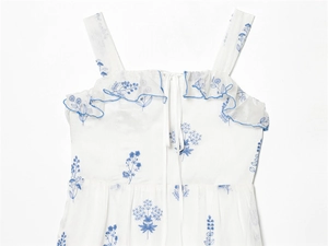 Detail of white dress with delicate blue floral embroidery and ruffled neckline
