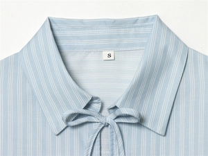 Close-up of light blue striped poplin shirt neckline with stylish bow-tie and size S label