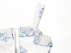 Detail of blue floral print on white chiffon dress with delicate ruffled edges