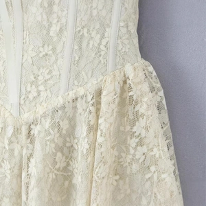 Close-up of floral lace dress with bone structure and ruffled hem in cream white color