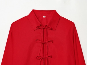 Detail of red poplin blouse featuring elegant three-bow tie closures and classic collar