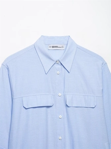 Detail of light blue striped shirt featuring two front flap pockets and white buttons