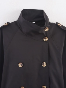 Detail of high collar black trench coat with tortoiseshell buttons and shoulder epaulettes