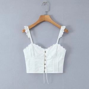 Close-up of white lace camisole featuring delicate ruffles and metal button details