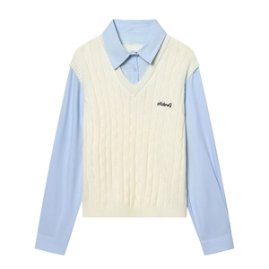 Détail du gilet en maille torsadée avec broderie NatureQ et col de chemise bleu