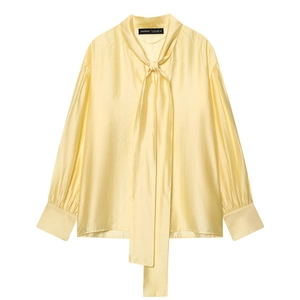 Detailed close-up of light yellow silk-like shirt fabric with elegant neck-tie design
