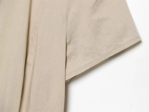 Close-up detail of high-quality beige cotton linen fabric with uniform stitching on shirt