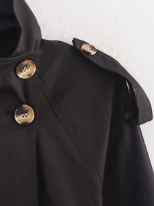 Detail of black trench coat shoulder with tortoiseshell buttons and epaulette design