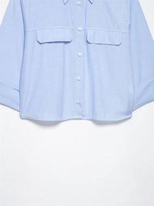 Detail view of light blue striped short shirt with white buttons and flap pockets