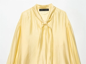 Detail of elegant pussy-bow neckline and pleated shoulders on a satin blouse