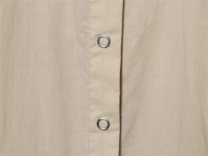 Detail of beige cotton fabric with high-density weave and polished metal grommets