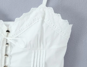 Close-up of white camisole top featuring delicate lace trim and ribbon bow detail