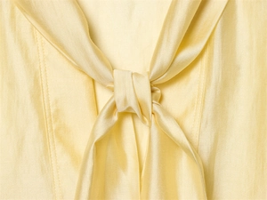 Detailed close-up of light yellow satin shirt neckline featuring a silk-textured bow tie