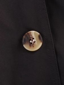 Macro detail of tortoiseshell pattern button and double stitching on brown trench coat