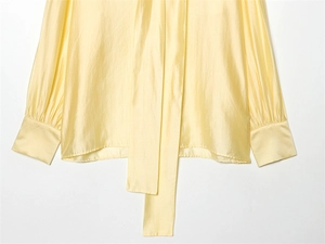 Detail of pale yellow satin shirt showing smooth metallic luster and long neck tie