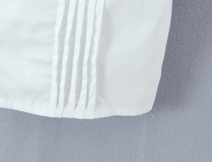 Close-up of white lace camisole showing delicate pin-tucks and precise hemline stitching