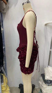Détail de robe bordeaux à paillettes montrant le laçage au dos et la jupe à sequins