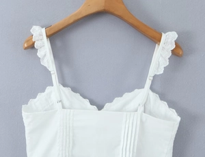 Detail of white camisole with adjustable eyelet lace straps and pleated cotton fabric