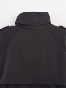 Detail of black trench coat collar featuring shoulder epaulettes with tortoise buttons