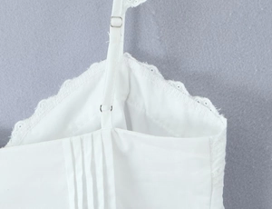 Detail of adjustable thin shoulder straps with lace trim and pleated white fabric texture