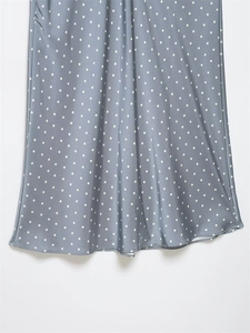 Macro detail of silky satin fabric texture and white polka dots on grey-blue midi skirt