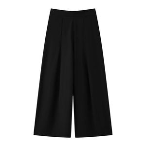 Detail of high-waist black wide-leg trousers featuring sharp pleats and draped fabric