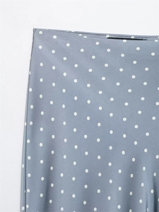 Detail view of smooth blue satin skirt waist featuring white polka dots and elegant texture