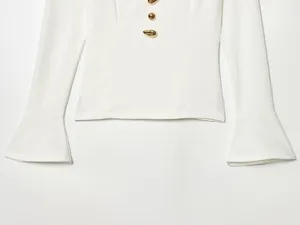 Dettaglio della camicetta bianca con eleganti maniche a campana e bottoni dorati
