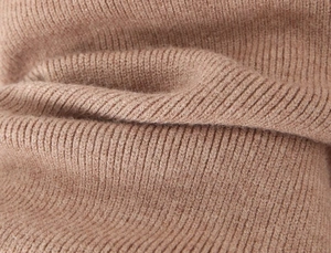 Vue macro du tissu en maille côtelée camel montrant la texture douce et les fibres