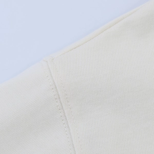 Close-up of premium cream knit fabric showing high-quality stitching and fiber texture