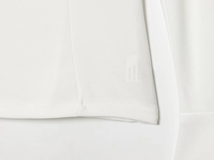 Dettaglio delle cuciture e dell'orlo del top bianco in chiffon con scollo a V del set