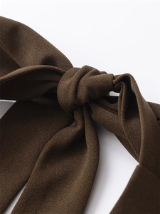 Detail shot of a dark brown crepe fabric bow tie design on a slim fit dress