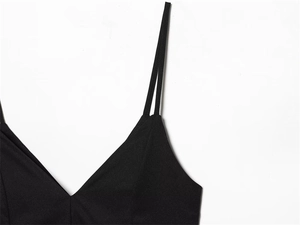 Detail of a black deep V-neck dress showing fine woven texture and delicate shoulder straps