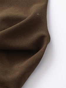 Macro detail of dark brown crepe fabric showing fine grain texture and elegant drape