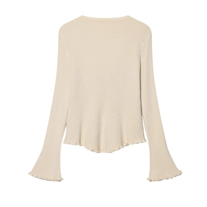 Dettaglio del cardigan in maglia albicocca con polsini a campana e bordi ondulati