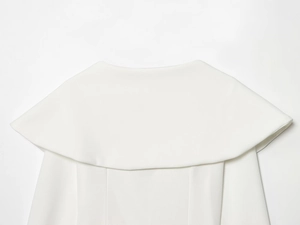 Dettaglio del set bianco con scollo a V che mostra la trama del tessuto e il collo a mantella