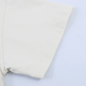 Detailed close-up of double-stitched hem on cream satin-spliced t-shirt sleeve