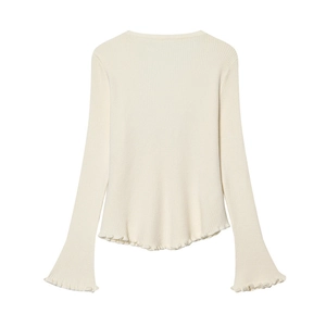 Dettaglio del cardigan in maglia crema con trama a coste verticali e bordi a volant